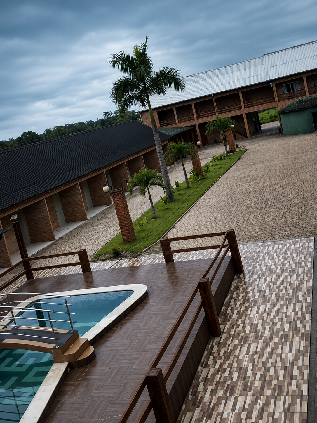 Fachada do Villa Green Hotel, com colunas de tijolo, luminárias e palmeiras